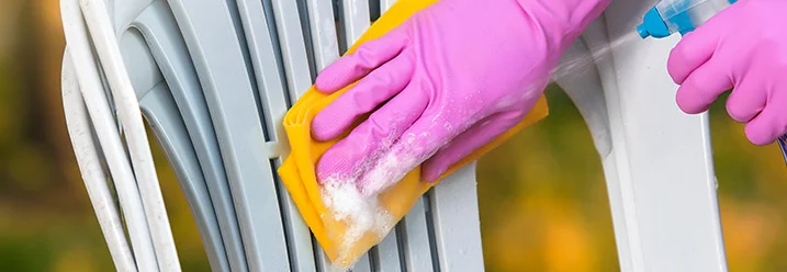 Person reinigt Gartenstuhl